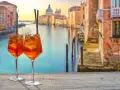 Zwei Aperol Spritz auf einem Holztisch mit Blick auf den Canal Grande in Venedig. Perfekt für einen Aperitif in der spritz bar.