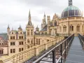 Schweriner Schloss mit seinen Türmen und Kuppeln. Ein Steg führt über Dächer, ein toller Ort, um zu entdecken, was man in Schwerin machen kann.