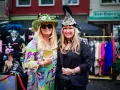 Zwei Frauen in bunten, auffälligen Outfits und Hüten genießen das Lindenthaler Sommerfest.