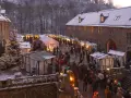 Schneebedeckter Weihnachtsmarkt in einer Burg, ein echter Geheimtipp NRW. Besucher schlendern zwischen festlich beleuchteten Buden.