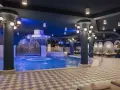 Ein luxuriöses Schwimmbad im Efteling-Stil mit Wasserspielen und Entspannungsbereichen.