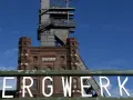 Das alte Bergwerk Prosper Haniel mit seinem markanten Förderturm ragt gegen einen blauen Himmel auf.