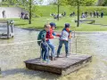 Drei Jungen auf einem Floß im Wasserspielplatz, der an ein Schiffshebewerk erinnert.
