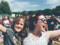 Zwei lachende Frauen, eine davon ein Kind, genießen das vivawest family festival. Glitzer auf den Wangen und eine Blume im Haar.