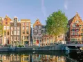 Bunte Grachtenhäuser spiegeln sich im Wasser. Fahrräder säumen den Kanal. So viel **was kann man in Amsterdam machen**!