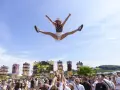 Eine Frau macht einen Spagat in der Luft vor einer Bühne bei einem der Festivals NRW. Die Menge jubelt.
