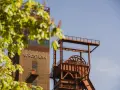 Industriearchitektur im Nordsternpark Gelsenkirchen: Ein markanter Förderturm und das Gebäude mit der Aufschrift "NORDSTERN" vor blauem Himmel.