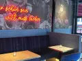Wilma Wunder: Neonlicht über blauer Bank und floraler Tapete. Wer schön sein will, muss lachen.