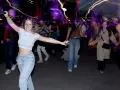 Junge Leute mit Kopfhörern, die im Dunkeln tanzen gehen, umgeben von bunten Lichtspuren.