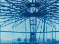 Bau des Riesenrades am GHH Oberhausen. Die Stahlkonstruktion ragt in den Himmel, Arbeiter sind auf der Spitze zu sehen.