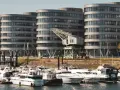 Moderne Gebäude am Duisburg Innenhafen mit vielen Yachten im Wasser. Ein alter Kran erinnert an die industrielle Vergangenheit.