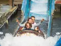 Familie hat Spaß auf einer spritzigen Wasserbahn im Freizeitpark.