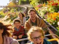 Familie lacht auf Achterbahnfahrt durch blühende Blumenpracht – ein Erlebnis im neuen Freizeitpark Deutschland.