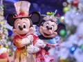Mickey und Minnie in festlichen Outfits vor Weihnachtsbäumen im Disneyland. Ein magisches Weihnachtserlebnis!