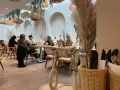 Gemütliches Café mit Boho-Deko, geflochtenen Lampen und Trockenblumen. Gäste genießen ihren soul brunch in entspannter Atmosphäre.