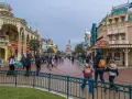 Menschen schlendern die Hauptstraße entlang, vorbei an Geschäften und dem Schloss. Ein Tag im Disneyland, vielleicht mit einem Disneyland Fastpass für die Attraktionen.