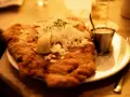 Ein knuspriges Schnitzel mit Zwiebeln und Zitrone, wie bei Oma Kleinmanns. Dazu ein Dip und ein Glas Wasser.