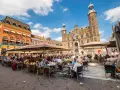 Lebhafter venlo markt mit vielen Menschen, die in Cafés unter Sonnenschirmen sitzen. Im Hintergrund das historische Rathaus.