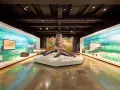 Im Museum steht ein riesiger Baumstamm, der an die Zeche erinnert. Links und rechts davon sind Ausstellungen mit Karten und Fossilien.
