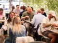 Leute genießen ein entspanntes St. Louis Frühstück im Freien, umgeben von Grün.