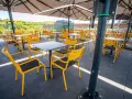 Leere gelbe Stühle und Tische unter Sonnenschirmen auf der Terrasse des Zeche Ewald Cafés.