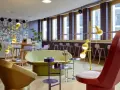 Ein bunter, moderner coworking space cologne mit auffälligen Möbeln, Comic-Wand und gelben Stehlampen.