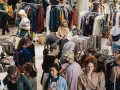 Menschen stöbern auf einem belebten **bazar de nuit** nach Kleidung und Accessoires.
