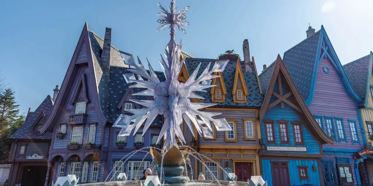 Ein eisiger Brunnen mit Schneeflocken-Dekor vor bunten Häusern, wie in einem **frozen Disneyland**.