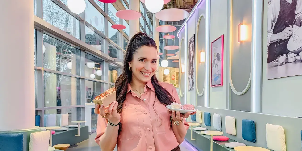 Frau hält süße Leckereien, perfekt zum Europapark Essen mitnehmen. Bunte Deko und gemütliche Sitzgelegenheiten laden zum Verweilen ein.