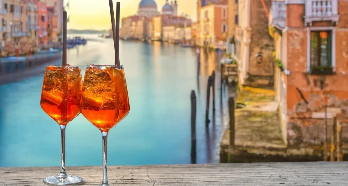 Zwei Aperol Spritz auf einem Holztisch mit Blick auf den Canal Grande in Venedig. Perfekt für einen Aperitif in der spritz bar.