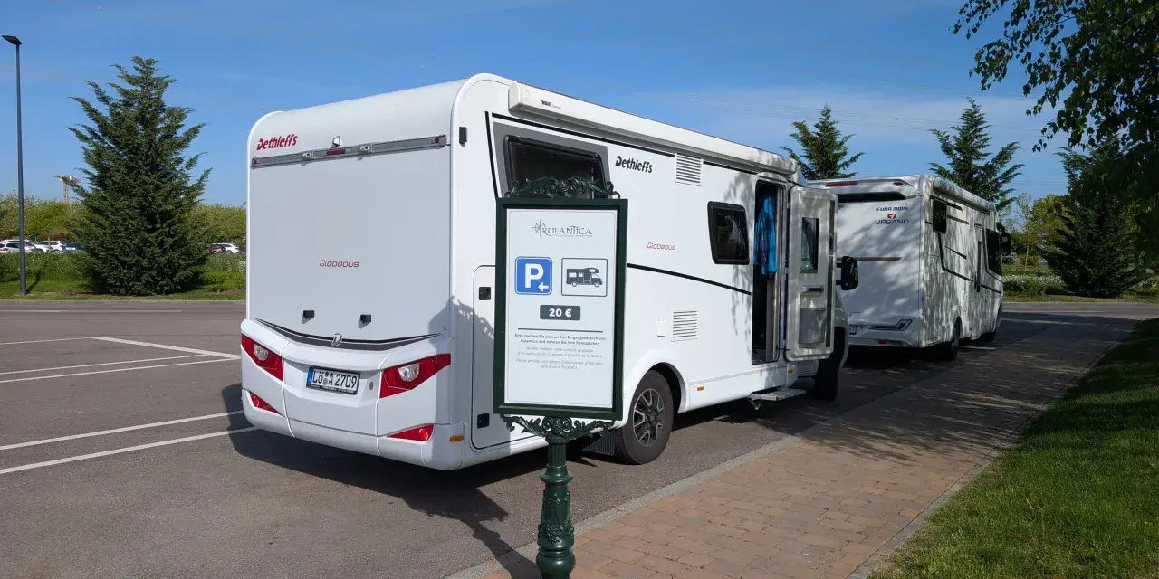Wohnmobile parken am Europapark. Ein Schild weist auf die Parkgebühr von 20 € für Rulantica hin.