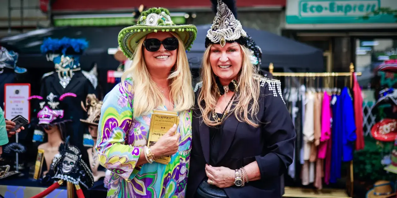 Zwei Frauen in bunten, auffälligen Outfits und Hüten genießen das Lindenthaler Sommerfest.