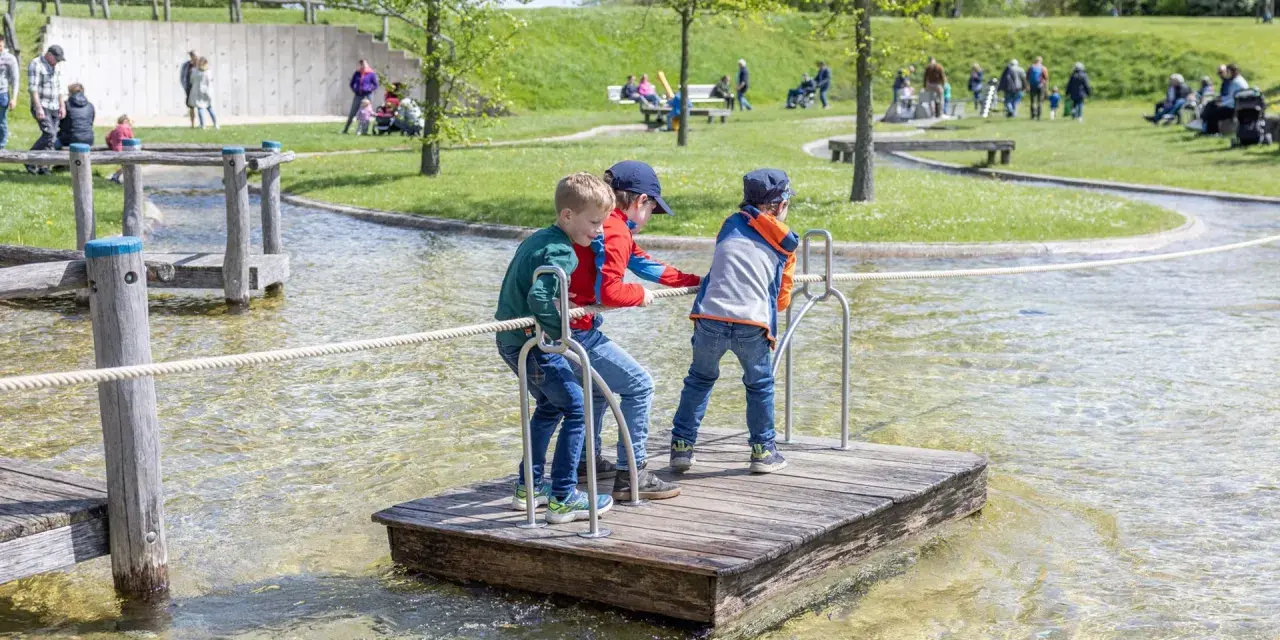 Drei Jungen auf einem Floß im Wasserspielplatz, der an ein Schiffshebewerk erinnert.