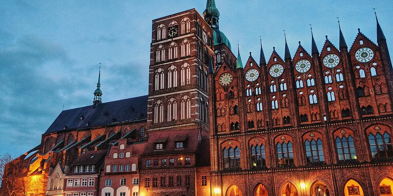 Abendstimmung auf dem Marktplatz der **Stralsund Altstadt**. Backsteingotik dominiert, mit dem Rathaus und der Marienkirche im Dämmerlicht.