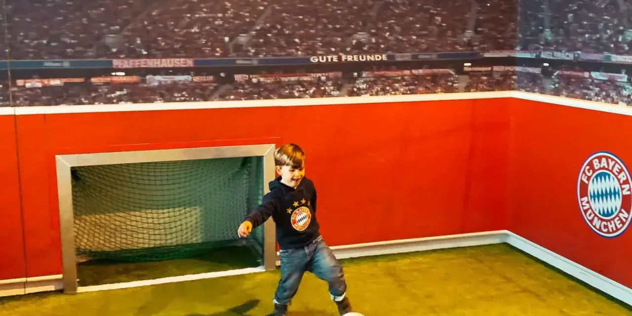 Kleiner Junge feiert seinen Allianz Arena Kindergeburtstag und kickt im FC Bayern Trikot.