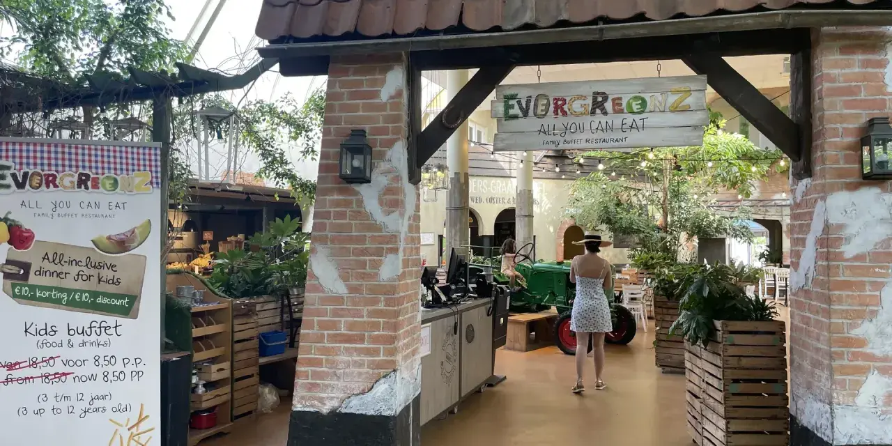 Im Center Parcs Restaurant "Evergreenz" lockt ein Buffet. Eine Frau im Sommerkleid geht vorbei.