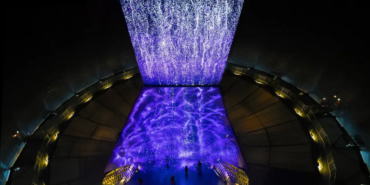 Im Gasometer Oberhausen erstrahlt eine Projektion aus tausenden Lichtpunkten, die wie ein Sternenhimmel oder ein Wasserfall wirken.
