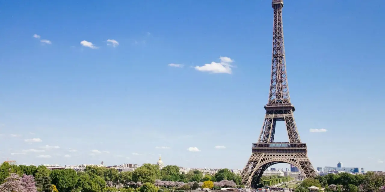 Eiffelturm in Paris, mit Menschen im Park. Hier gibt es viele Paris Tipps und Tricks für Ihren Besuch.