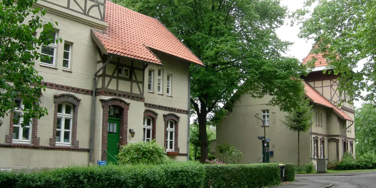 Fachwerkhäuser in der alten Kolonie Eving, umgeben von üppigem Grün und Bäumen.