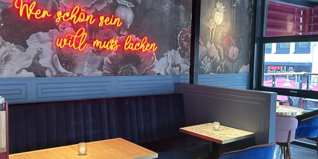 Wilma Wunder: Neonlicht über blauer Bank und floraler Tapete. Wer schön sein will, muss lachen.