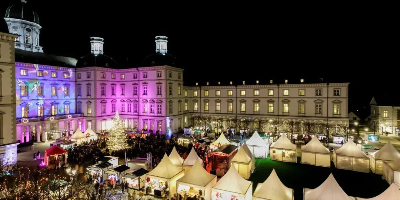 Einzigartiger Weihnachtsmarkt Bensberg vor beleuchtetem Schloss. Viele Stände und ein großer Weihnachtsbaum laden zum Bummeln ein.