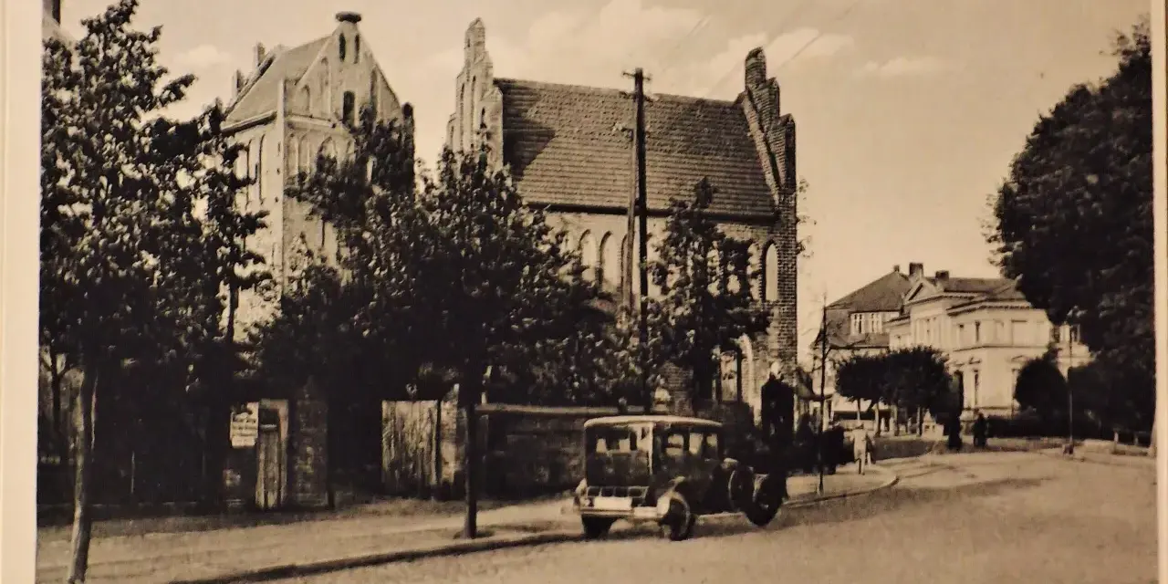 Alte Ansicht der Templiner Altstadt mit einem historischen Auto auf der Straße und markanten Gebäuden im Hintergrund.
