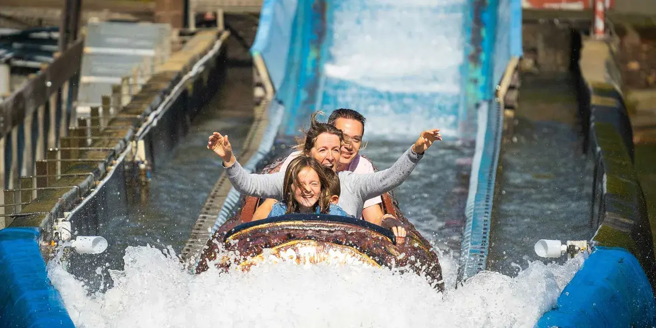 Familie hat Spaß auf einer spritzigen Wasserbahn im Freizeitpark.