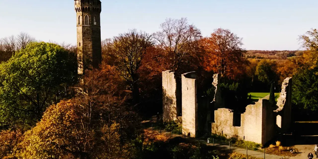 Herbstliche Szene mit dem alten Turm und Ruinen der **Dortmund Syburg** im warmen Licht.