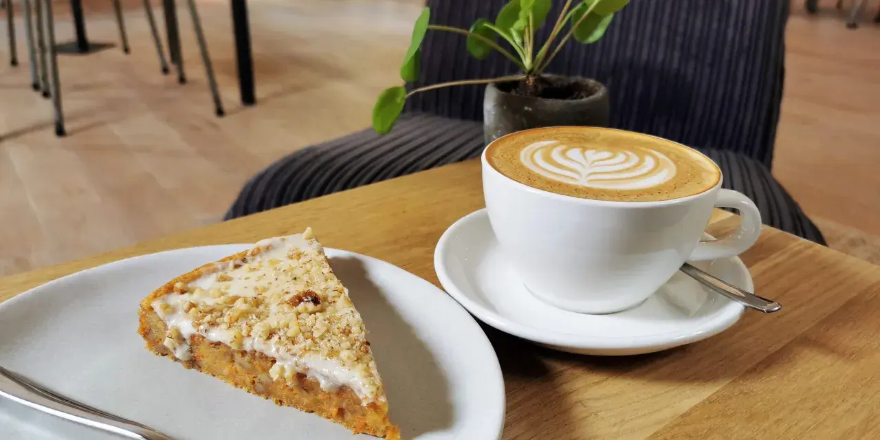 Ein Stück Kuchen mit Nüssen und eine Latte Art im **Kuchen Cafe**.