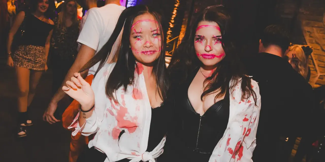 Zwei Frauen mit gruseligen Halloween-Schminkereien und blutigen Outfits feiern in der Halle Tor 2.
