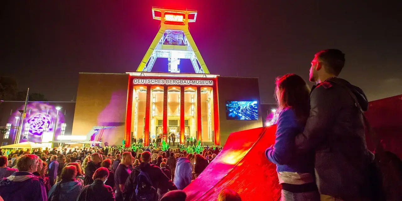 Ein Paar genießt die stimmungsvolle Nachtveranstaltung "Extraschicht Bochum" vor dem beleuchteten Deutschen Bergbau-Museum.