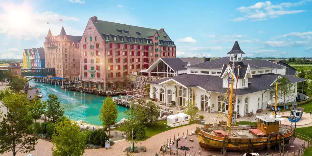 Ein malerischer Kanal fließt vorbei an bunten Gebäuden und einem alten Schiff. Das ist das charmante Themenhotel im Europa-Park.