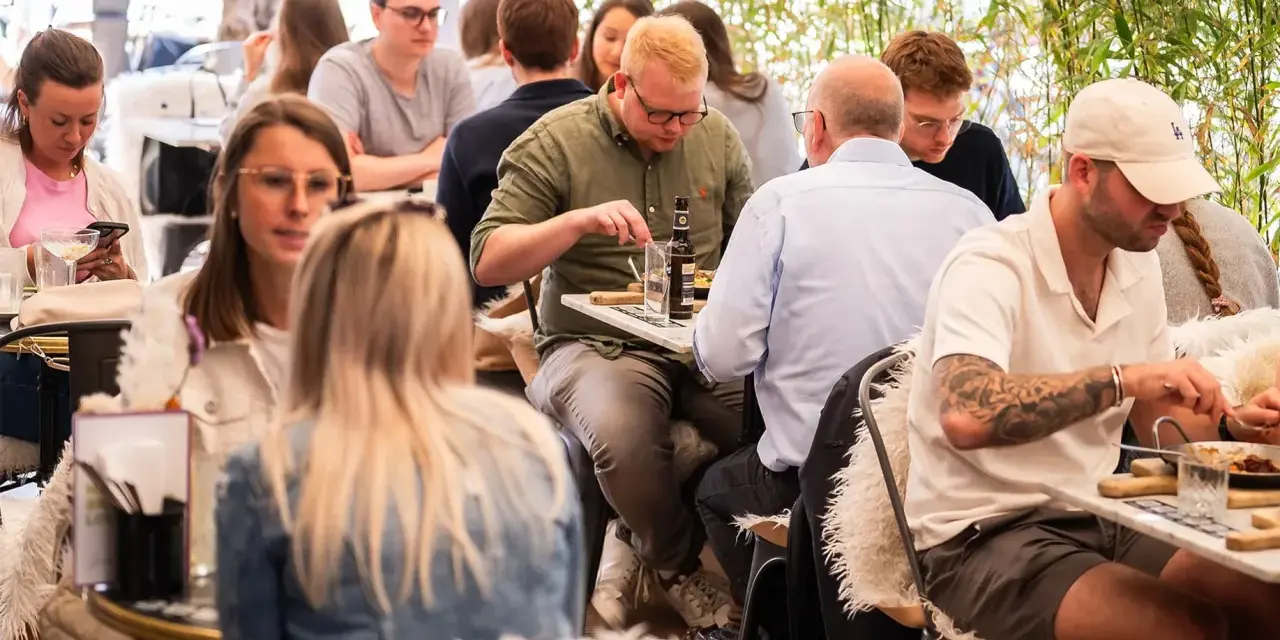 Leute genießen ein entspanntes St. Louis Frühstück im Freien, umgeben von Grün.
