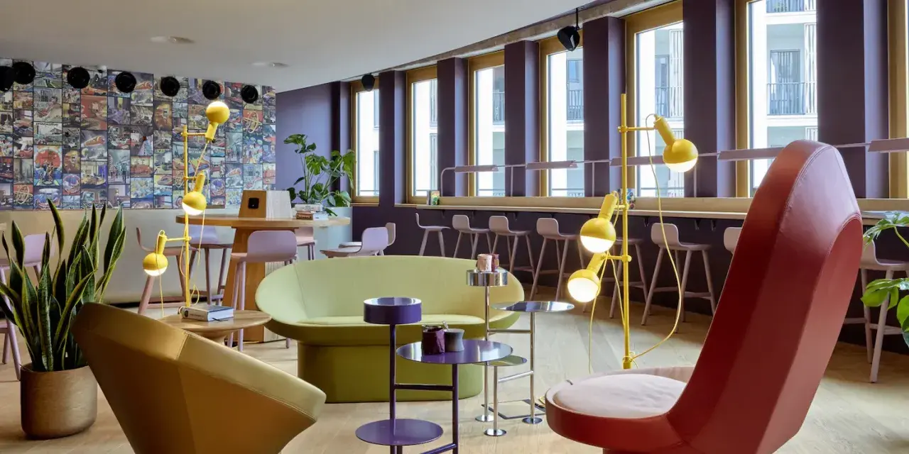 Ein bunter, moderner coworking space cologne mit auffälligen Möbeln, Comic-Wand und gelben Stehlampen.